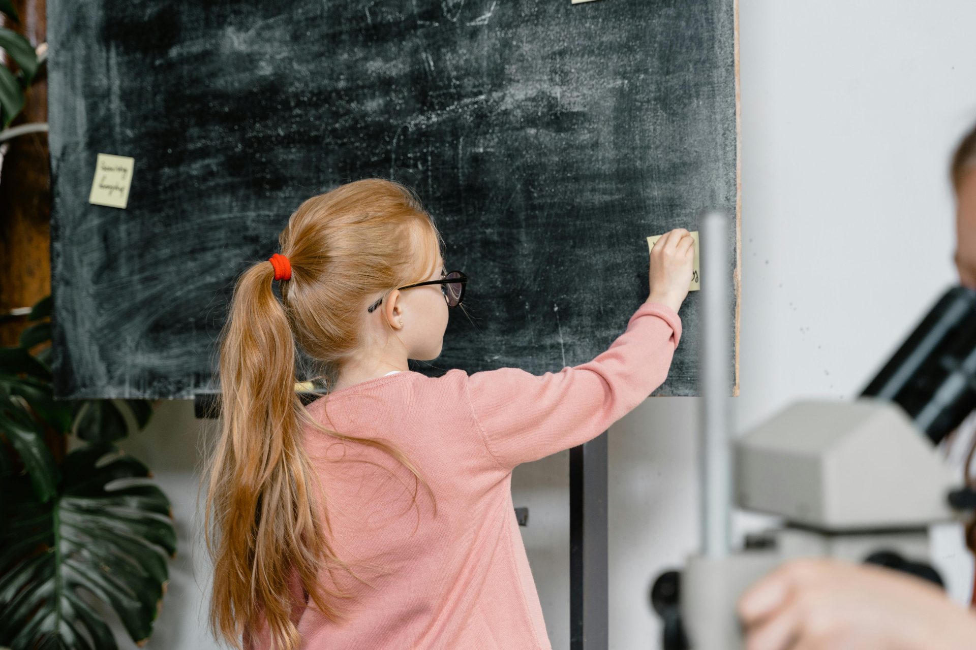 Child writing notes on blackboard in an educational environment.